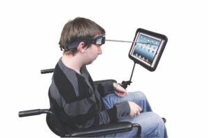 Man in wheelchair with headwand attached to forehead pointing at iPad screen